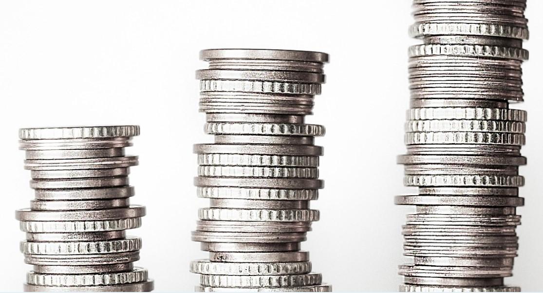 Tre staplar med silvermynt är placerade i stigande höjd från vänster till höger mot en vit bakgrund.